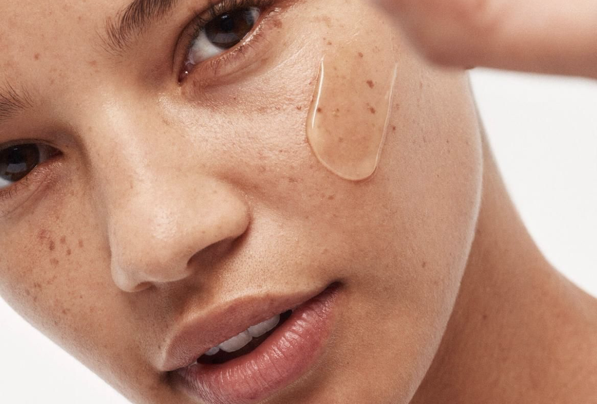 Close-up of a person's face with a skincare patch on their cheek against a white background